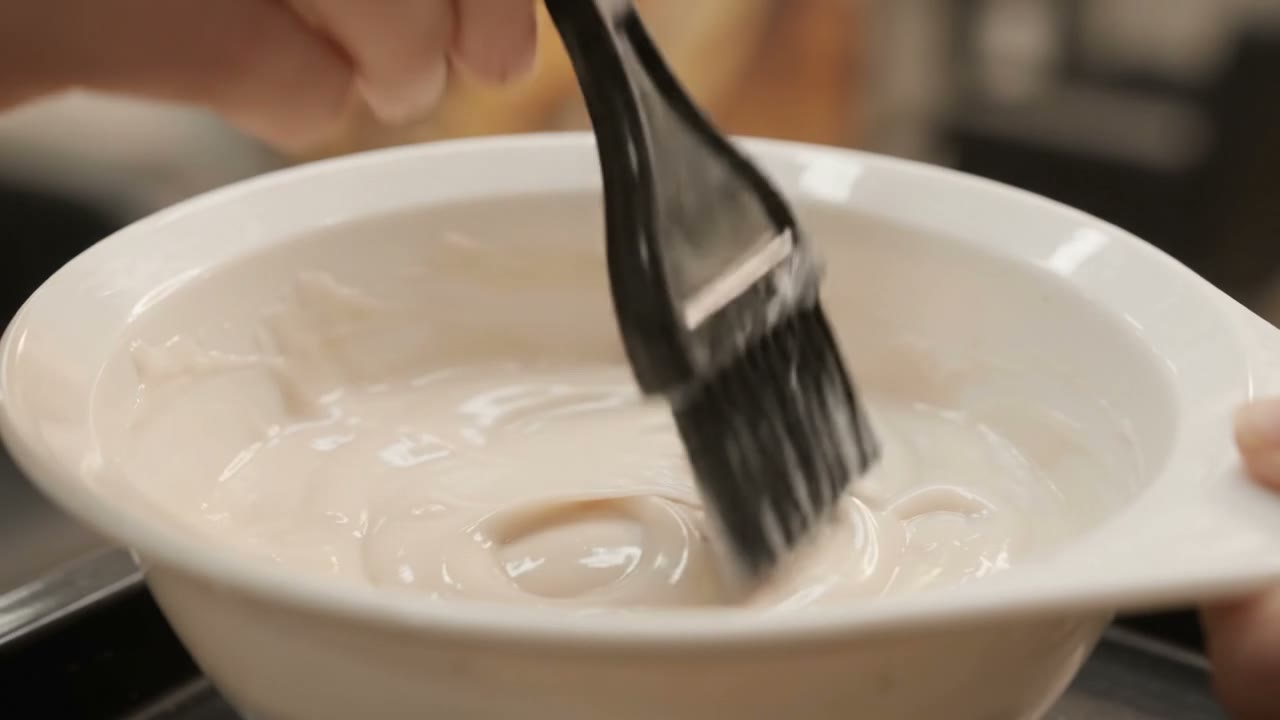 Colour being mixed in a bowl with a tint brush